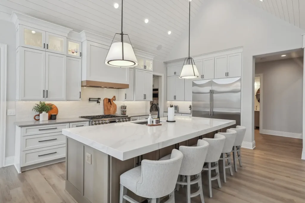 A kitchen features white cabinets complemented by black cabinet handles, a black faucet, and black-rimmed light fixtures