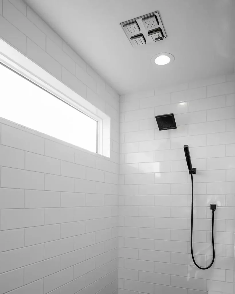 A black rain showerhead mounted on the wall of a luxury bathroom shower