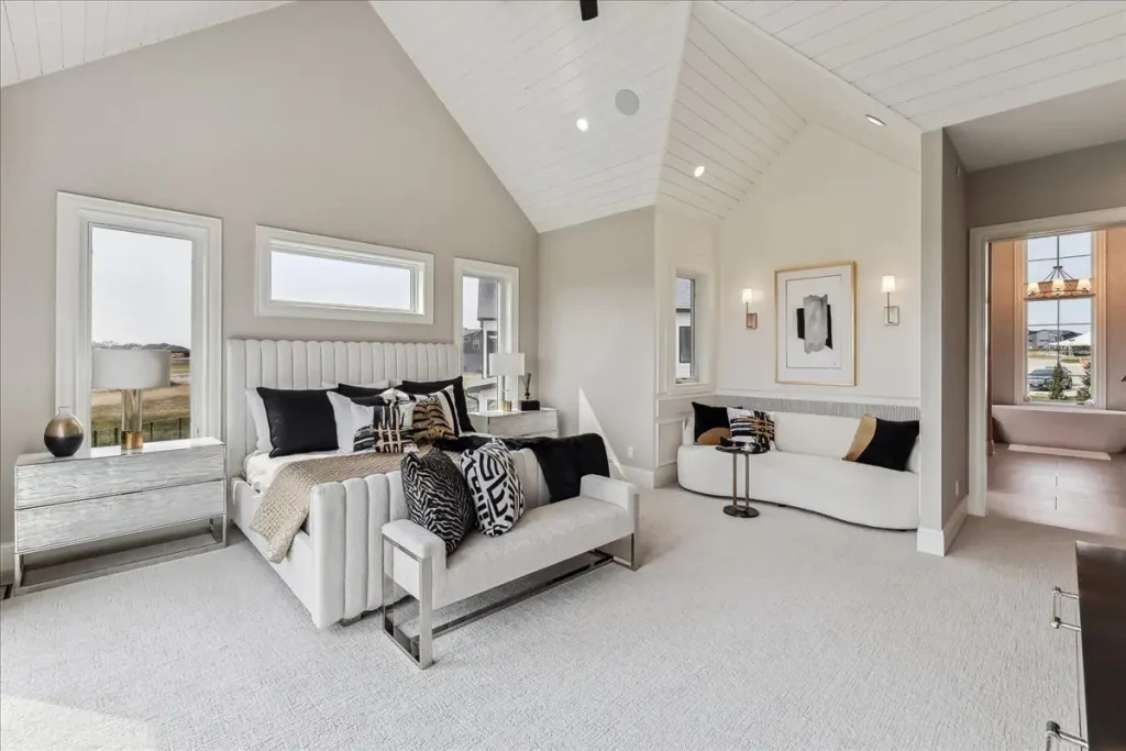 A modern luxury bedroom featuring a vaulted ceiling and reading nook