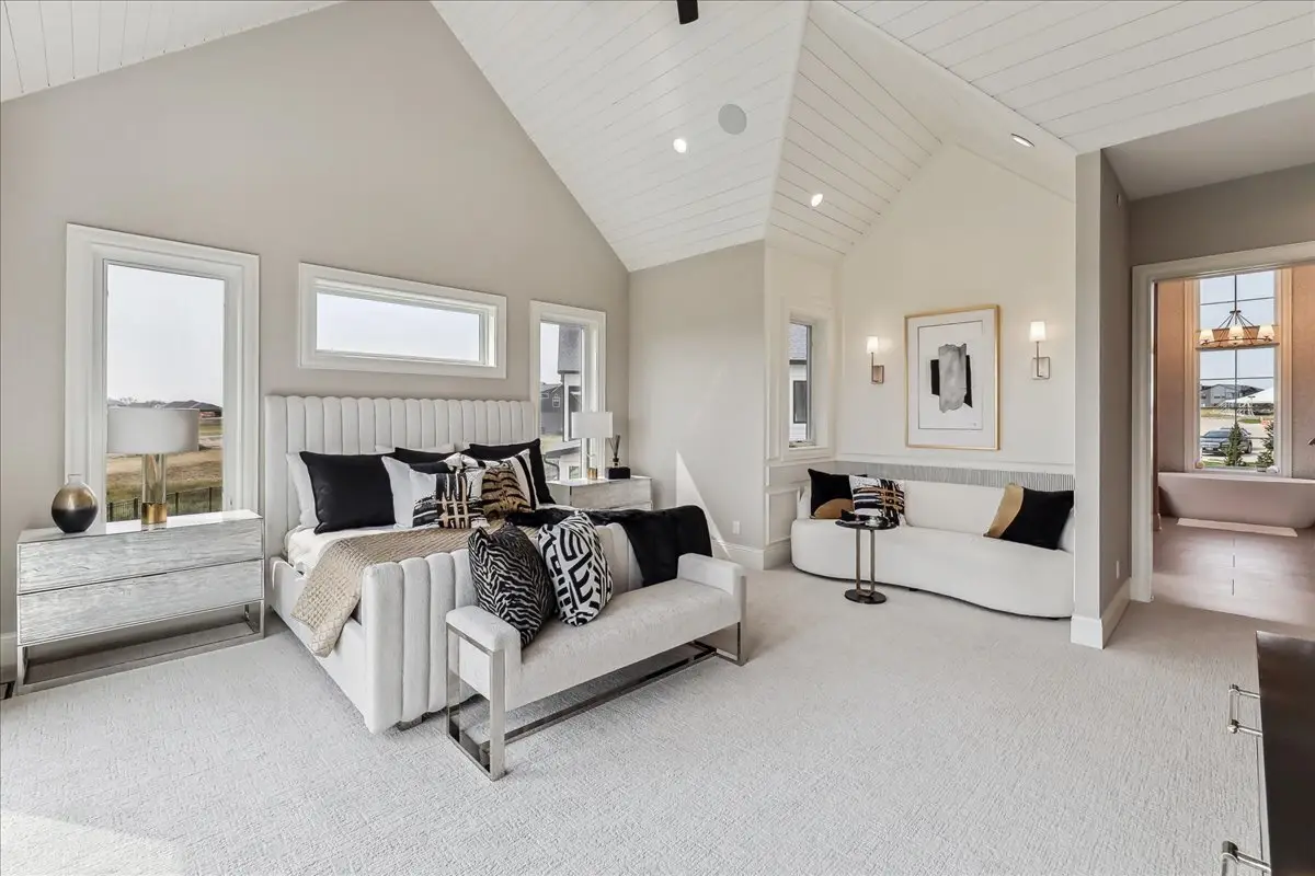 A modern luxury bedroom featuring a vaulted ceiling and reading nook