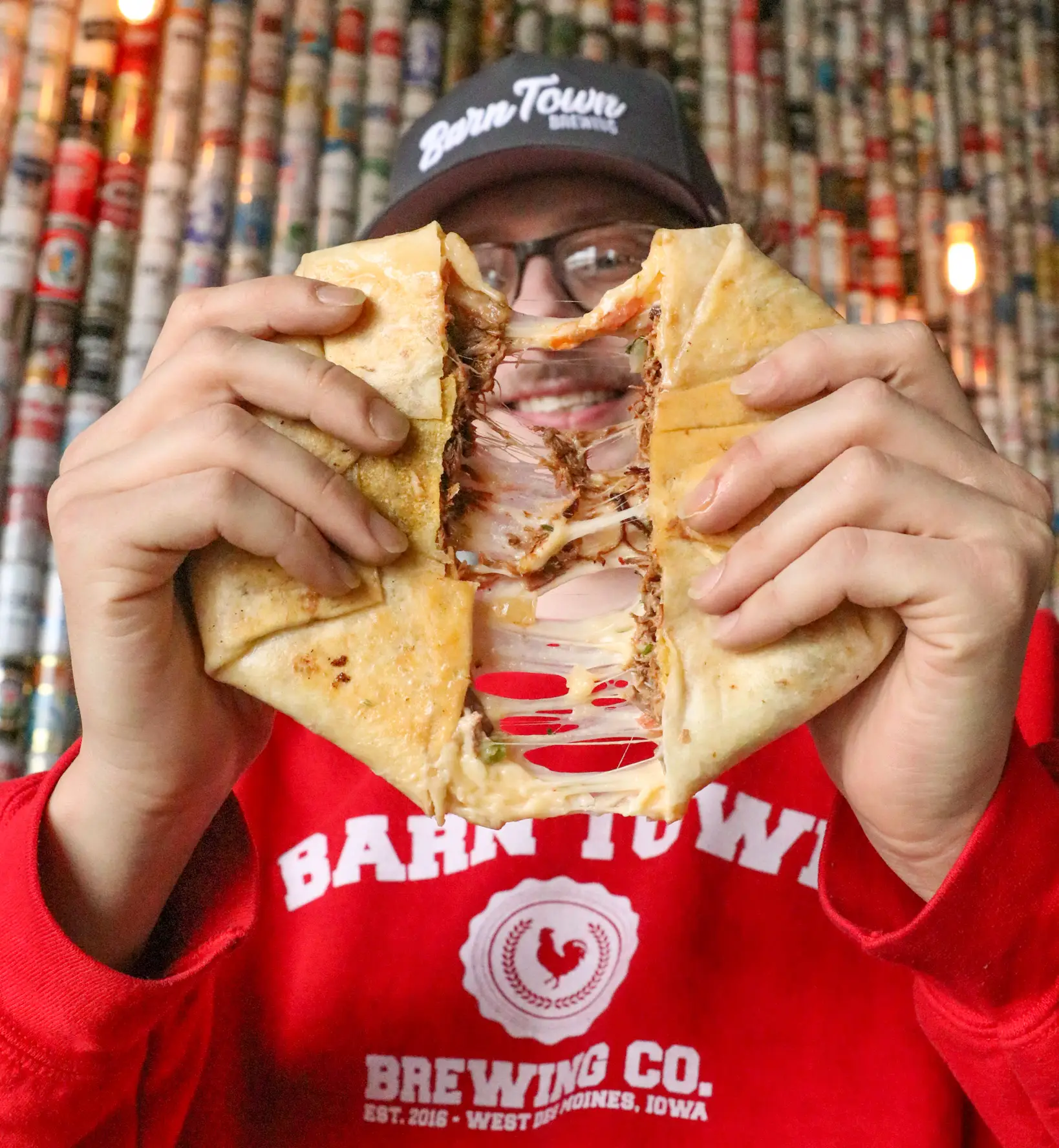 Loaded wrap or sandwich being pulled apart, showing melted cheese and a hearty filling inside. The close up highlights the texture and makes it feel fresh, warm, and really satisfying to eat.