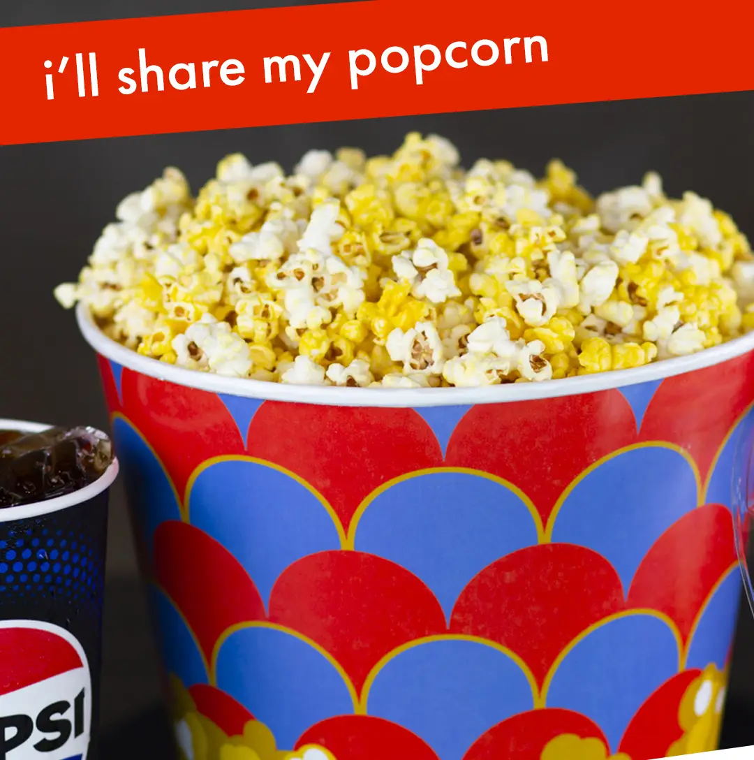 Bucket of popcorn filled to the top. Text at the top says “i’ll share my popcorn”. Drink cup next to the bucket. Dark background.